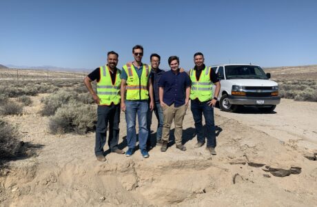 a group of men in yellow vests standing in a desert