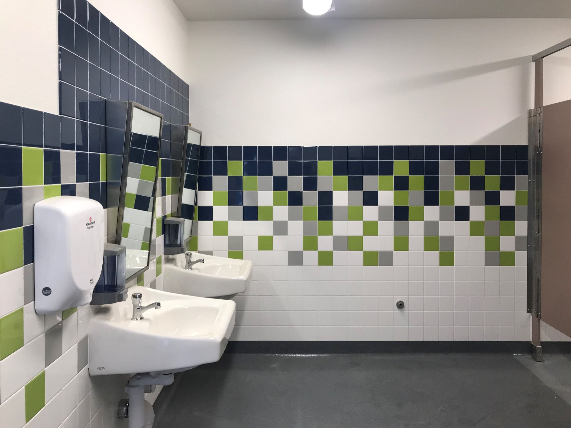 a bathroom with a urinal and sinks