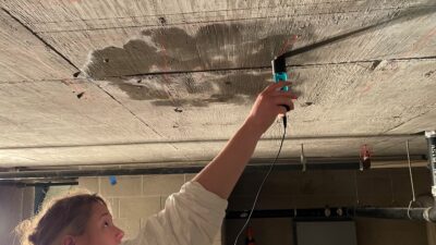person holding a sensor against a concrete ceiling