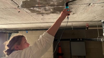 person holding a sensor against a concrete ceiling