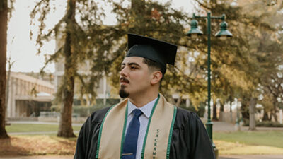 a man in a graduation cap and gown outdoors