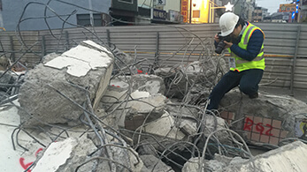 a man wearing a safety vest and safety vest working on a pile of debris